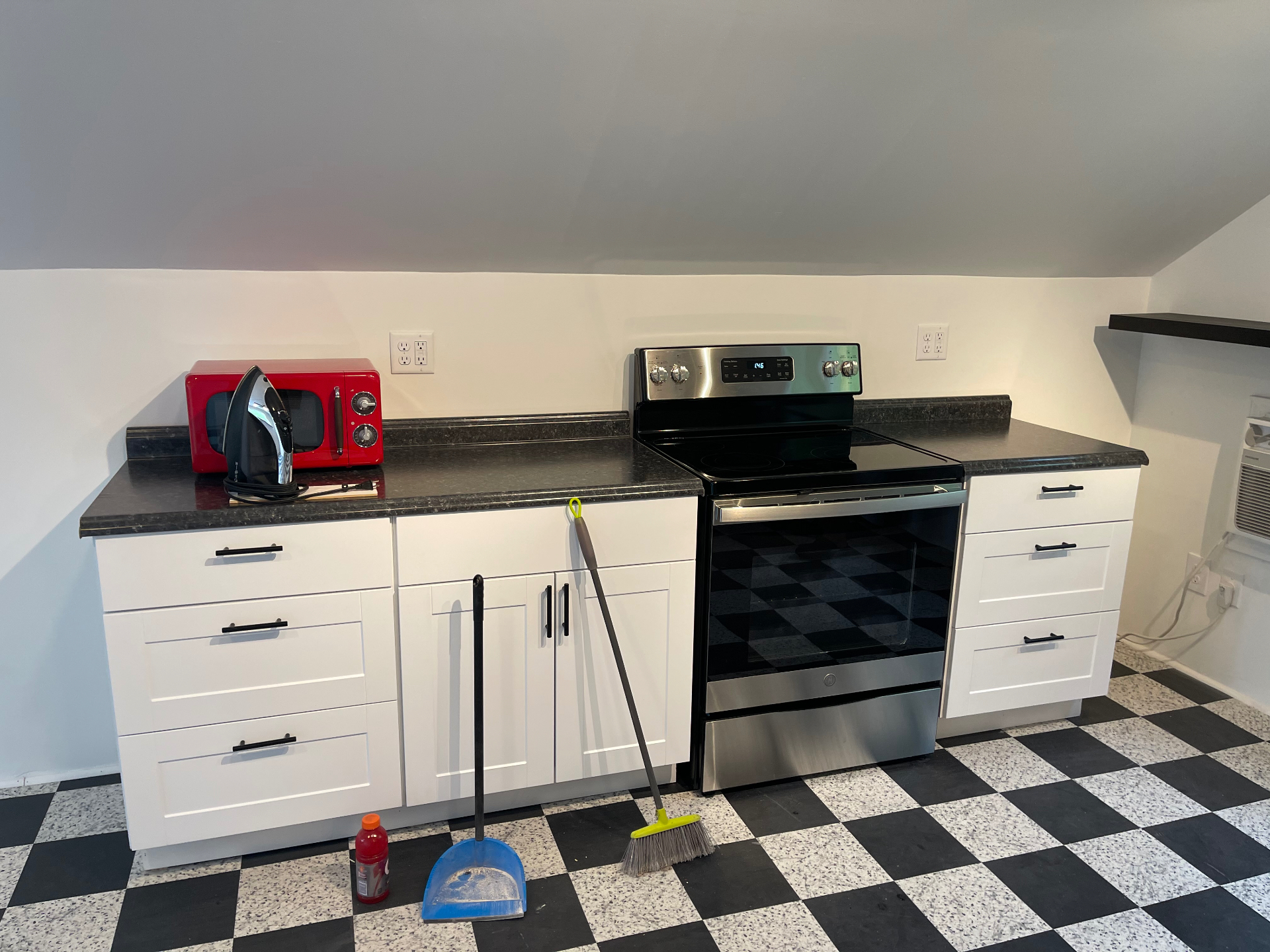 Renovated kitchenette with white shaker cabinets, granite counters, and stainless electric range